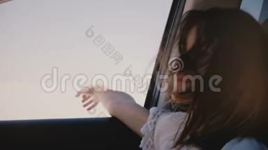 快乐的年轻旅游妇女，头发飞扬，手从窗外开着车，沿着阳光明媚的盐湖沙漠前进。